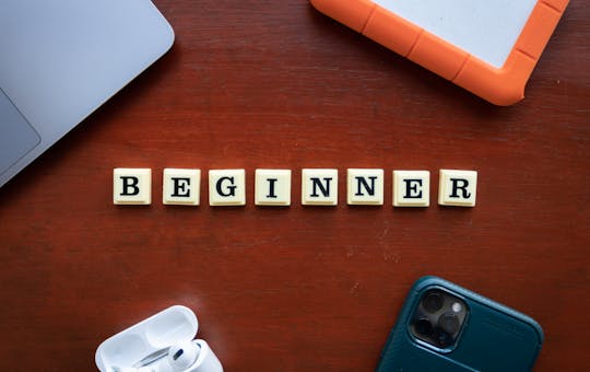 A top view of beginner workspace items including gadgets and letter dice on a wooden desk.